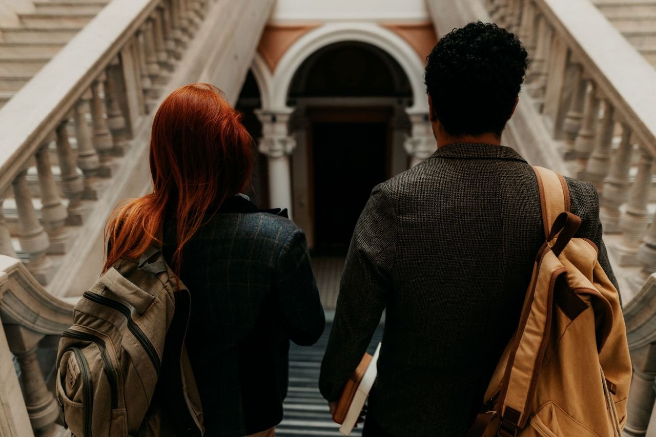 Two students walking through a historic university hallway in Buenos Aires.